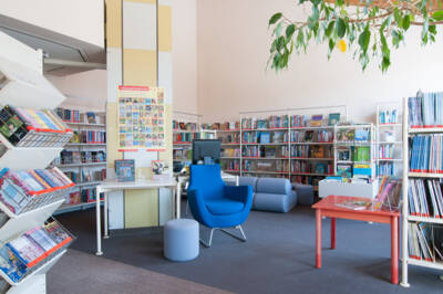 Blauer Lesestuhl steht vor einem Bücherregal mit vielen Büchern